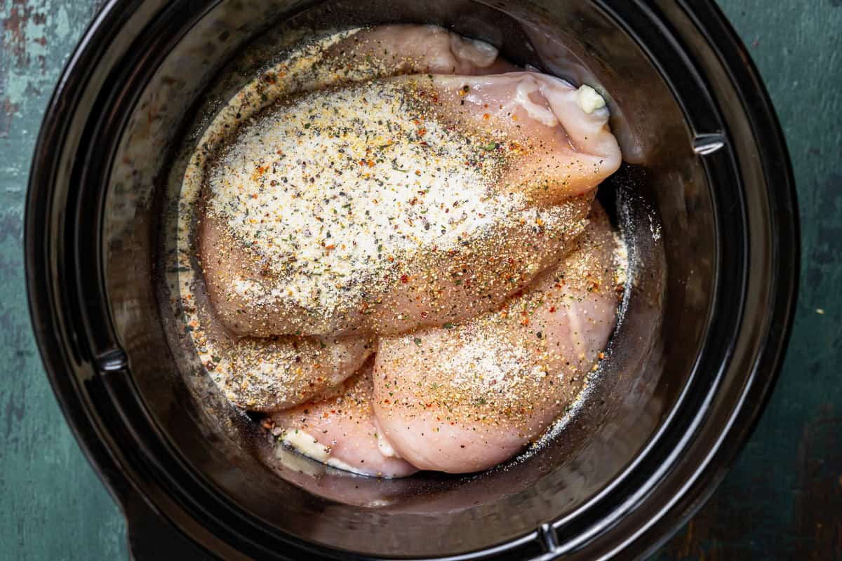 Chicken breasts with Italian dressing seasoning layered in a crock pot.
