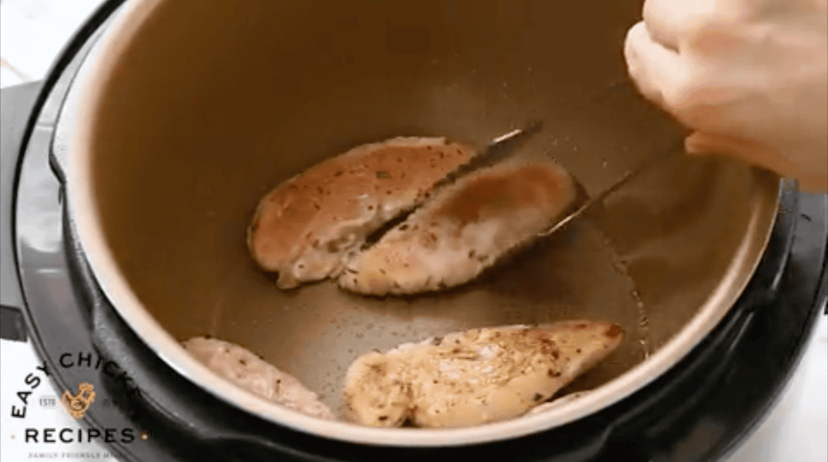 Flipping chicken tenderloins in a pressure cooker as they brown.