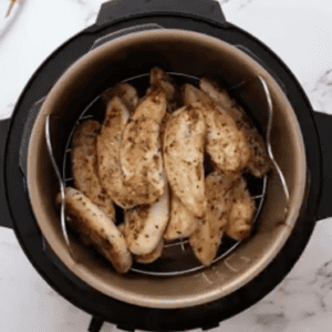 Chicken tenders stacked up on top of a trivet, in the Instant Pot.