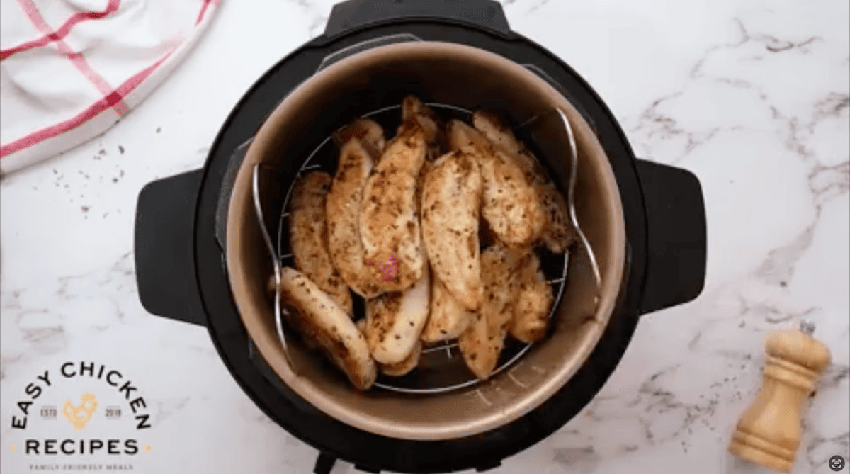 Chicken tenders stacked up on top of a trivet, in the Instant Pot.