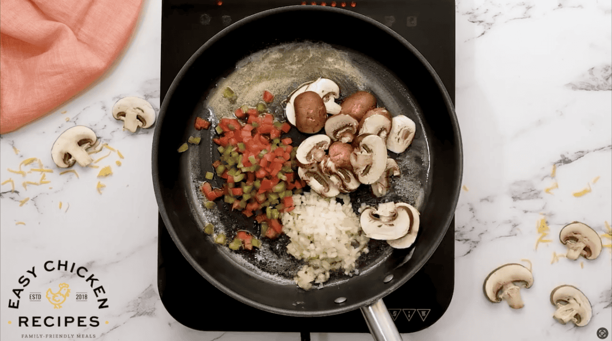 Diced onions, sliced mushrooms, and diced peppers in a skillet.