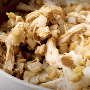 A mix of shredded rotisserie chicken and onions in a pan.