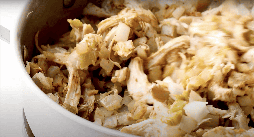 A mix of shredded rotisserie chicken and onions in a pan.