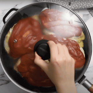 Hand placing a lid on a skillet.