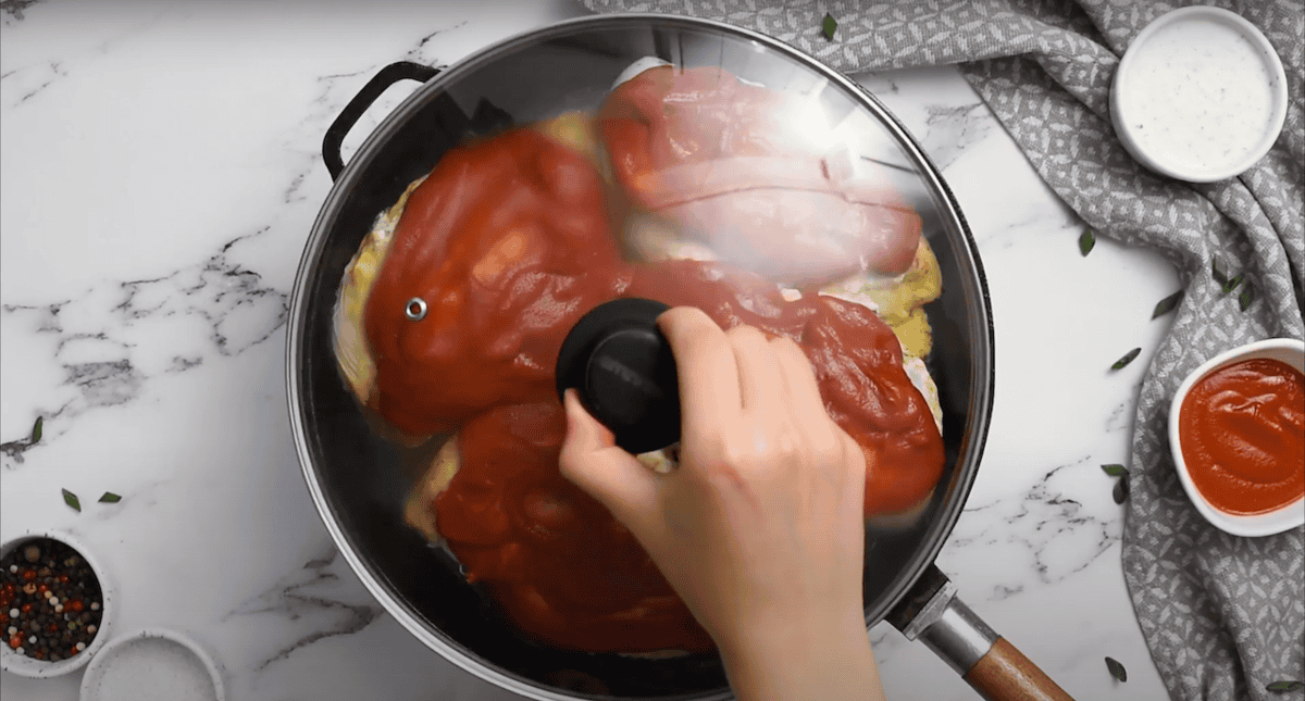 Hand placing a lid on a skillet.