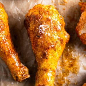 Oven fried chicken drumsticks on a parchment-lined tray.