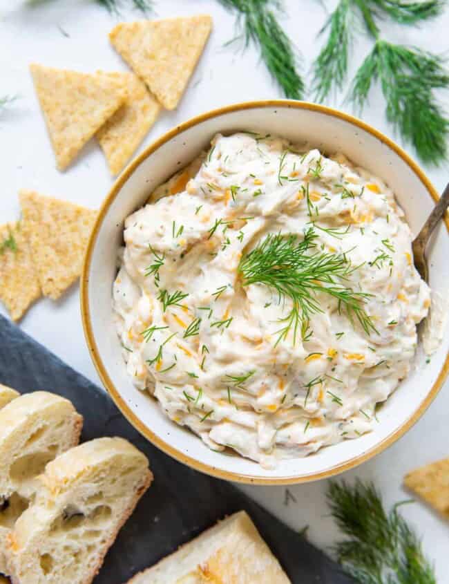 overhead view of a bowl of ranch chicken dip with crackers and pieces of bread surrounding it