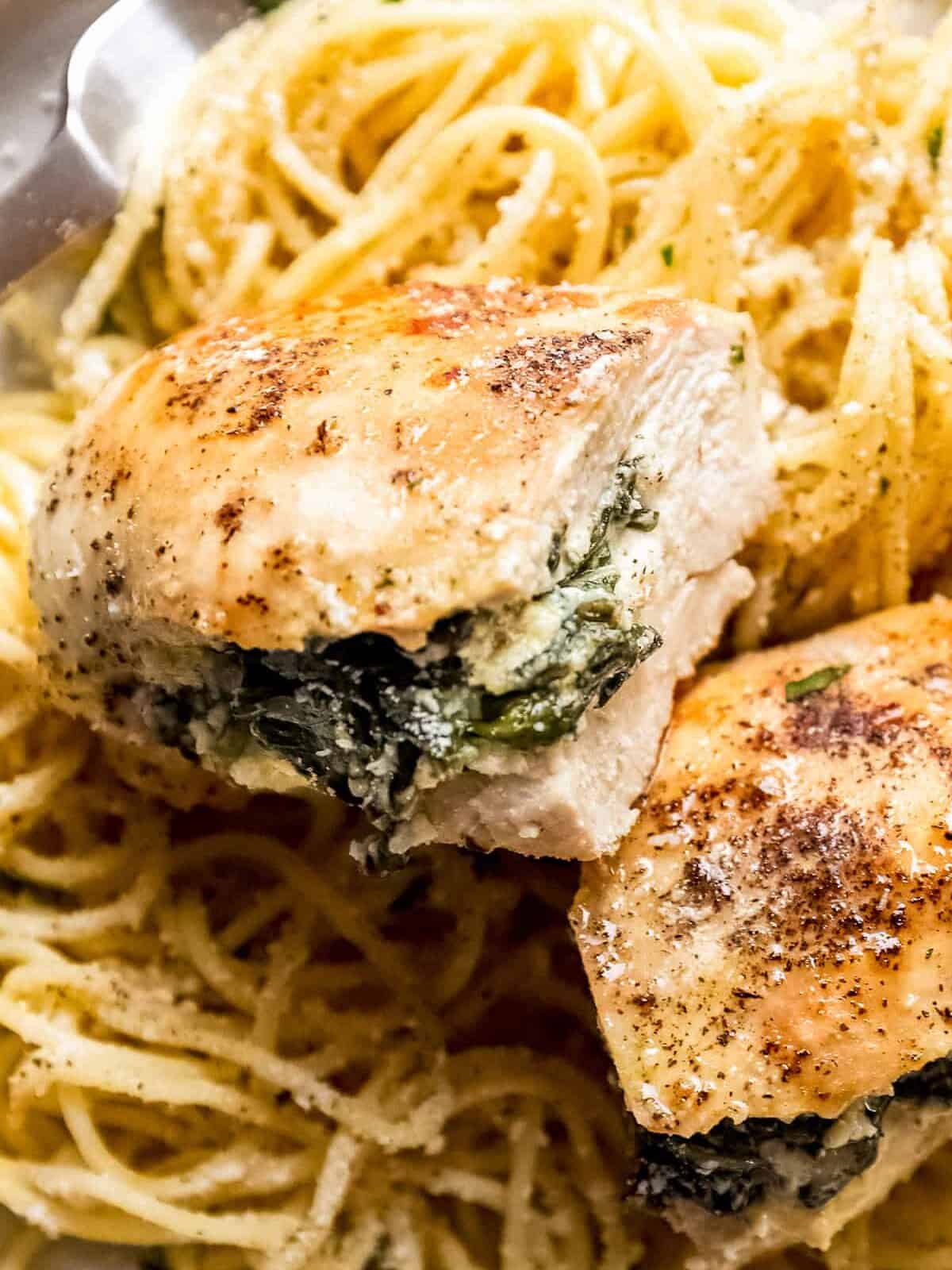 close up on spinach stuffed chicken breast on and spaghetti