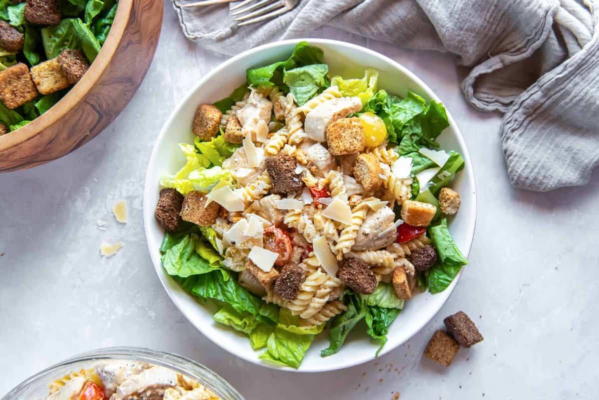 Chicken caesar pasta salad served in a bowl of lettuce, with croutons.