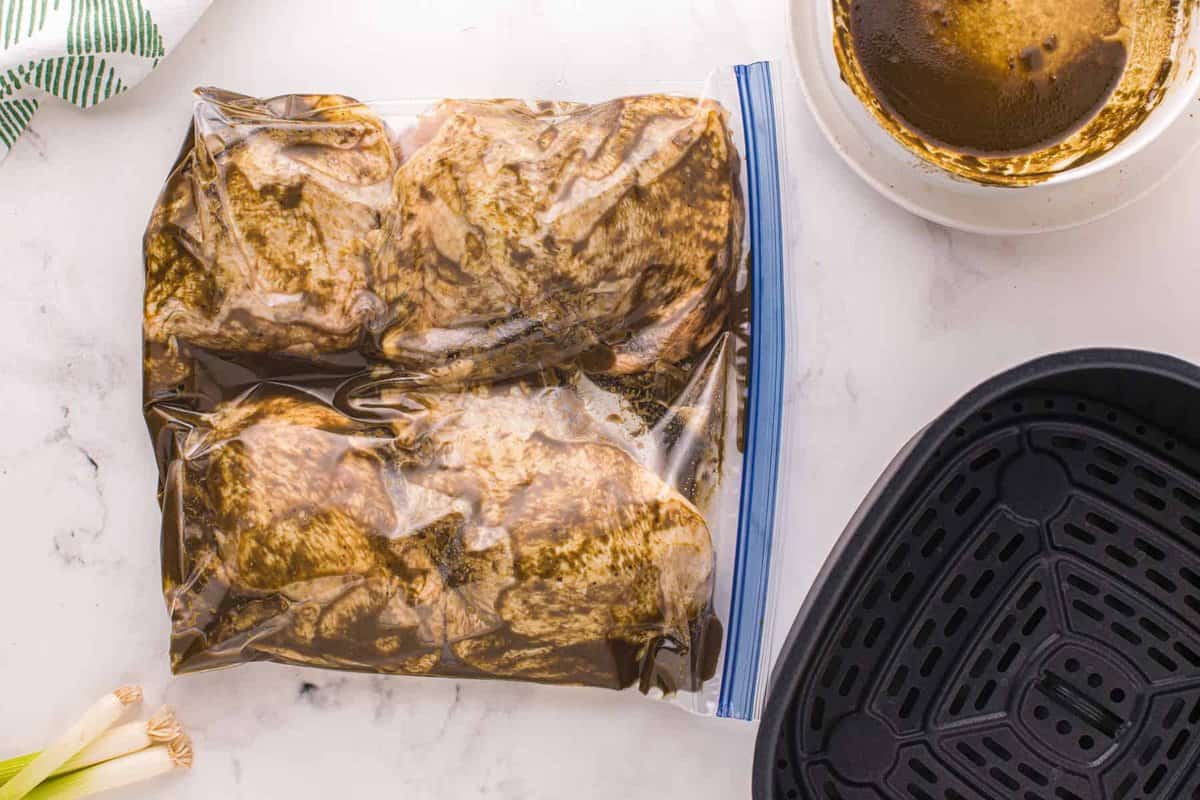 Chicken thighs marinating in a resealable bag.