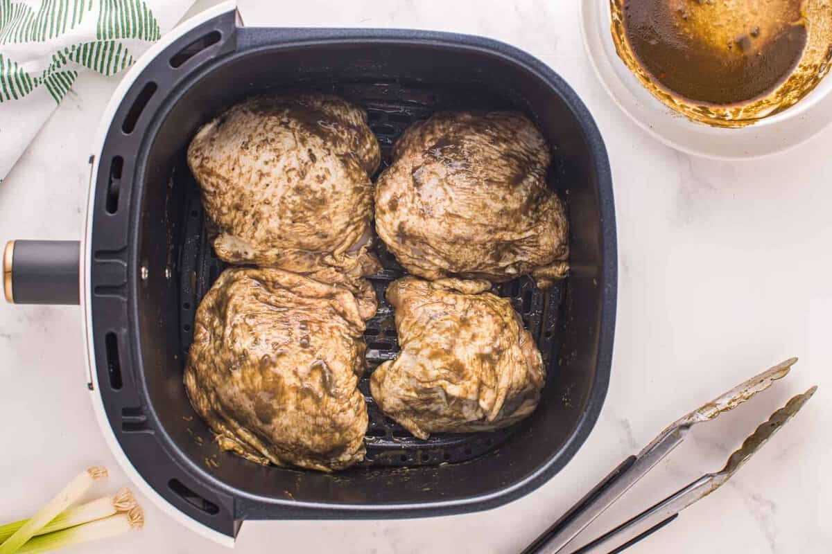 Marinated chicken thighs cooking in an air fryer