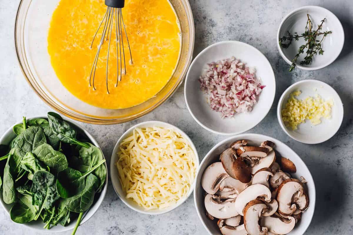 Ingredients for mushroom frittata recipe: mushrooms, eggs, spinach, cheese, and onions.