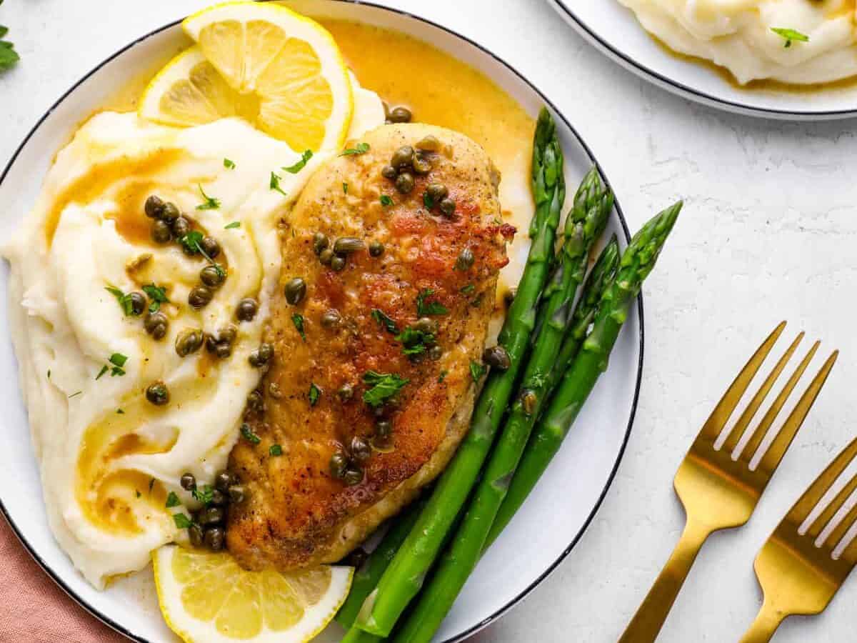 Gruyere stuffed chicken breast served on a plate with mashed potatoes, lemon piccata sauce, and capers.