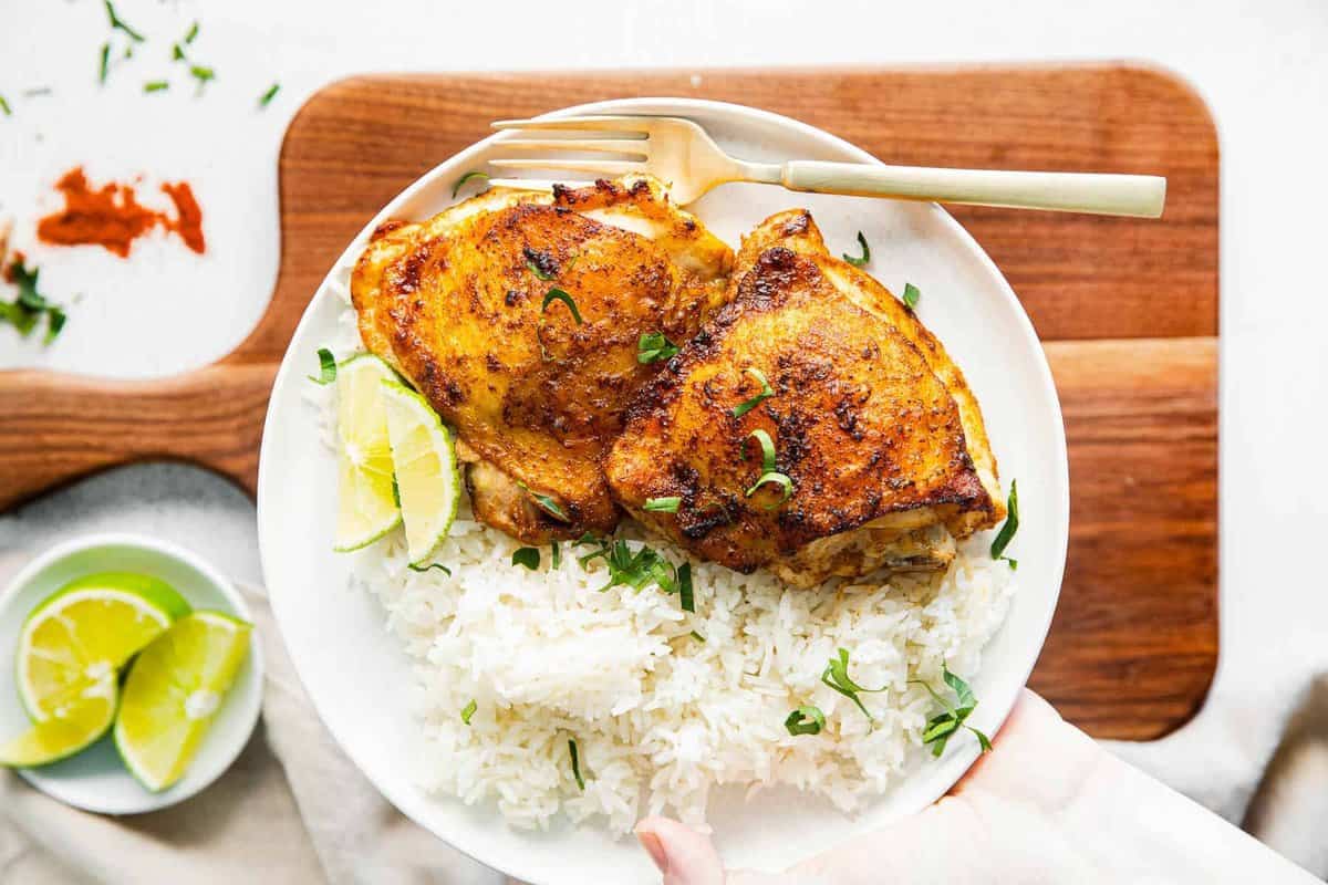 white plate with air fryer chili lime chicken thighs and rice
