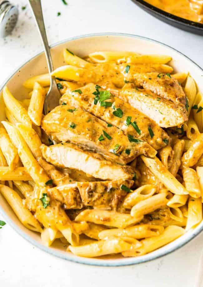 sliced chicken lazone over pasta in white bowl