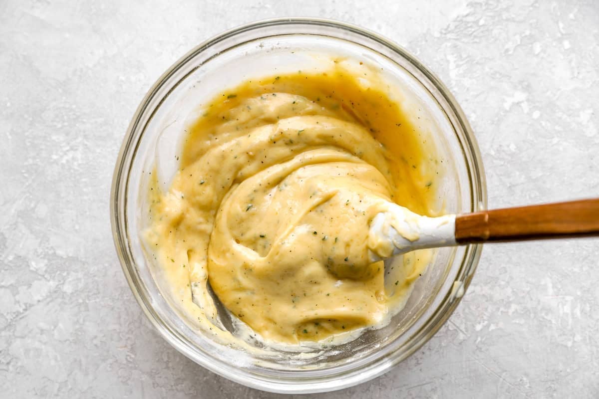 creamy ranch sauce in a glass bowl with a rubber spatula.