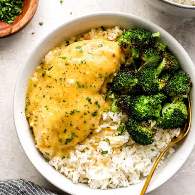 a serving of crockpot ranch chicken in a white bowl with rice and broccoli.