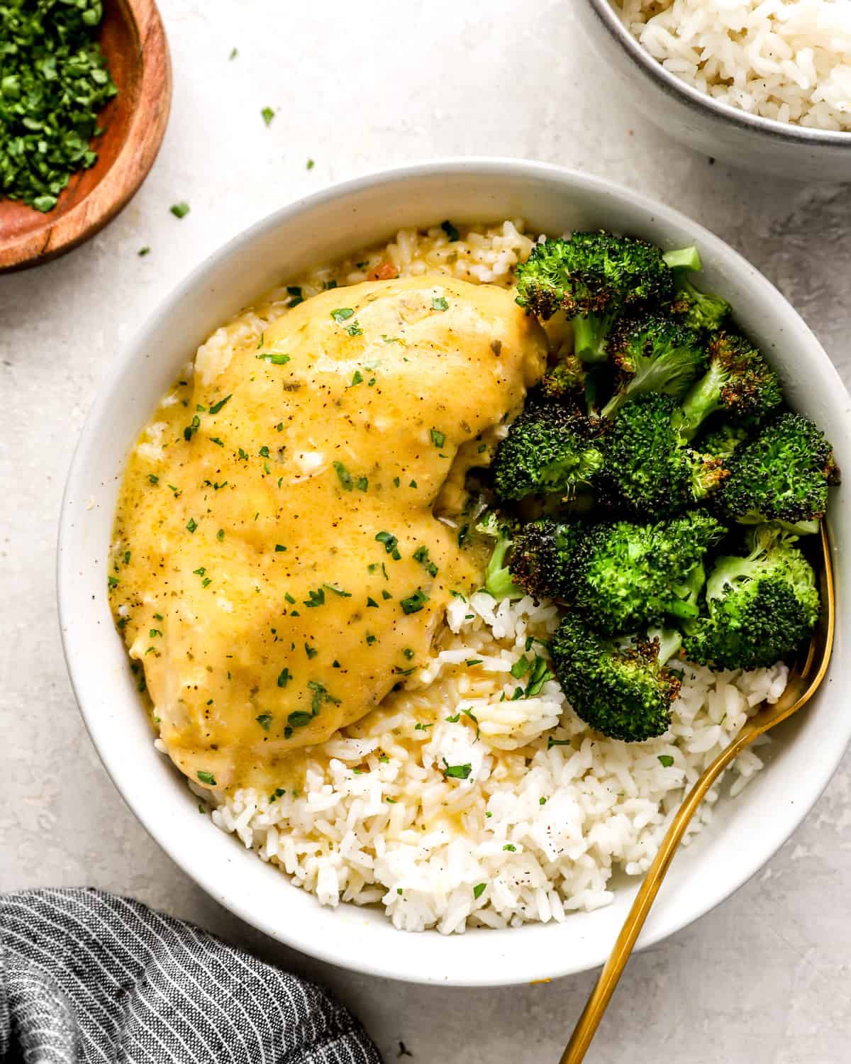 a serving of crockpot ranch chicken in a white bowl with rice and broccoli.