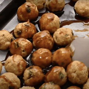 Coating meatballs in honey sesame glaze.