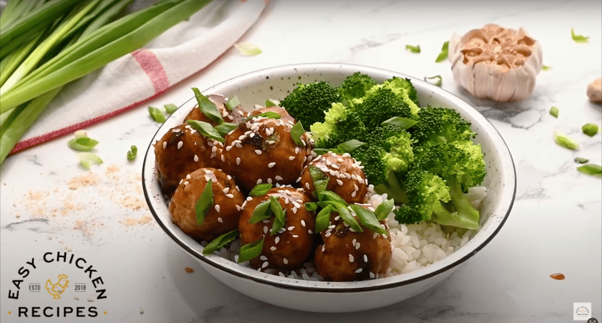 A bowl of white rice, broccoli, and asian chicken meatballs.