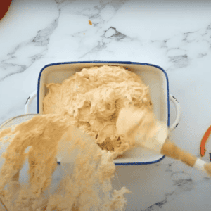 Pouring creamy dip mixture into a baking dish.