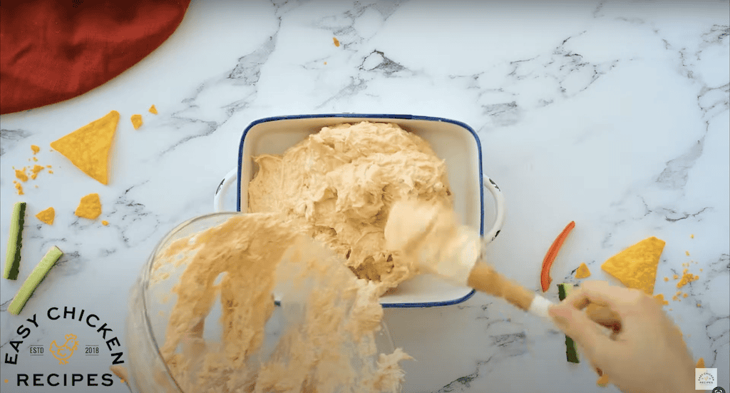Pouring creamy dip mixture into a baking dish.