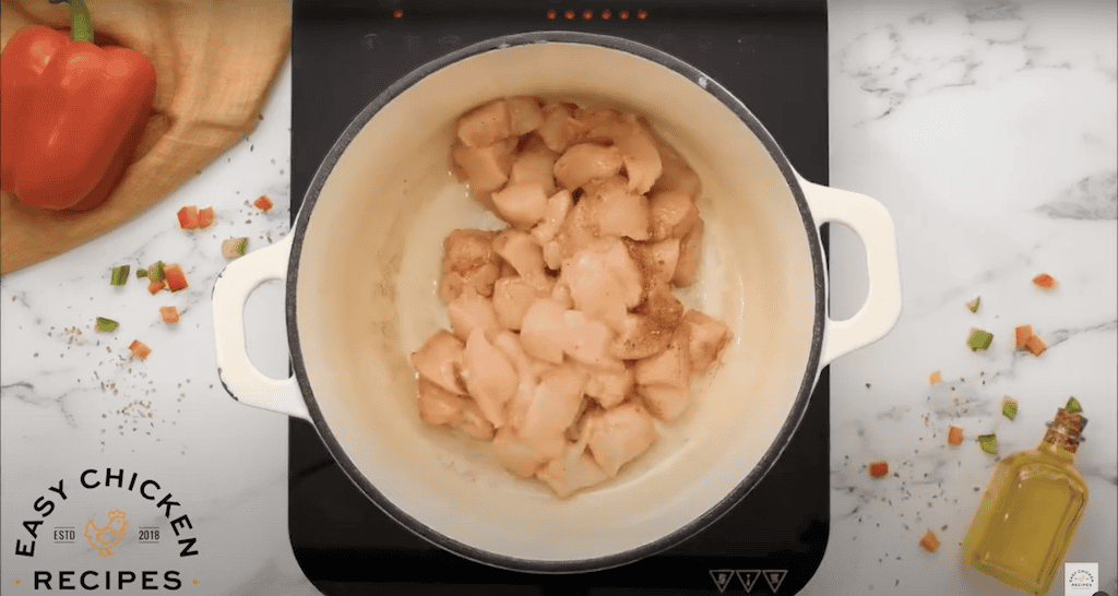 Cubes of chicken cooking in a large pot.