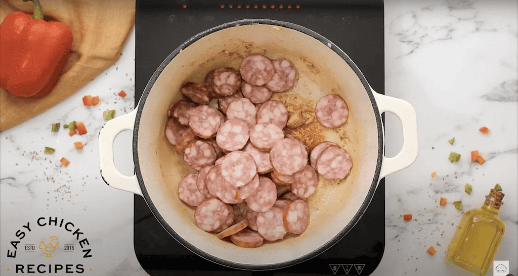 Slices of sausage cooking in a large pot.