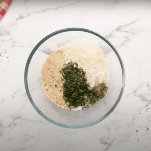 Breadcrumbs and seasonings in a glass mixing bowl.