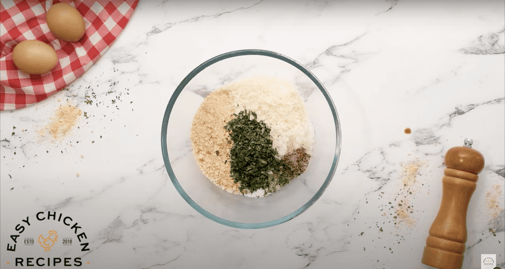 Breadcrumbs and seasonings in a glass mixing bowl.