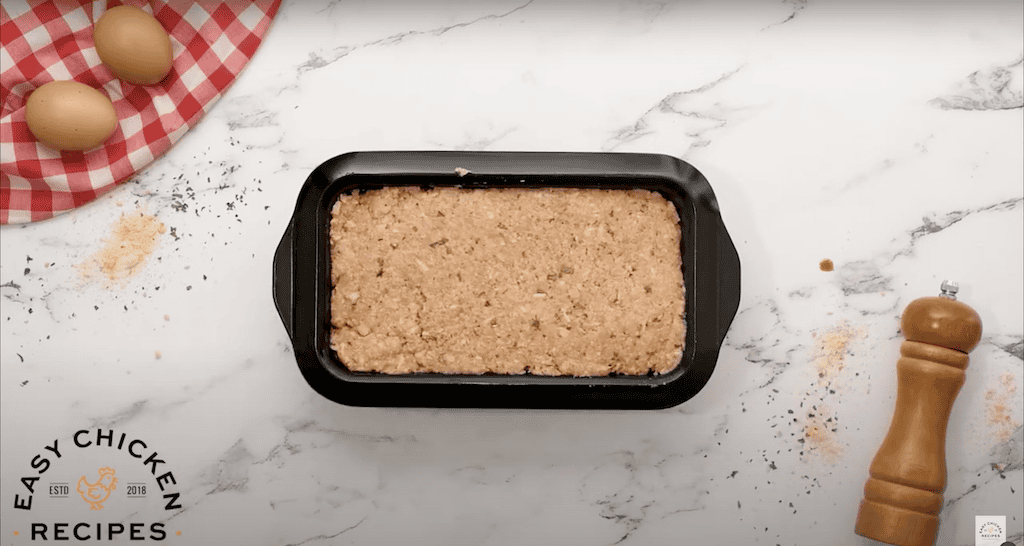 Ground chicken meatloaf mixture pressed into a loaf pan.