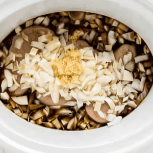 onions and garlic over seasoned chicken and soy sauce in a crockpot.