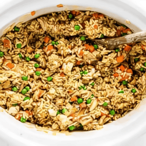 chicken fried rice in a crockpot with a wooden spoon.