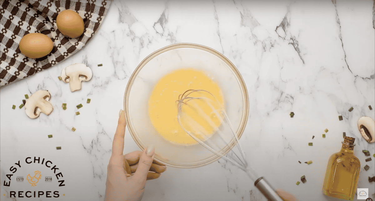 Beating eggs in a glass bowl, with a whisk.