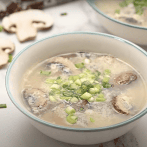 A bowl of egg drop soup with mushrooms.