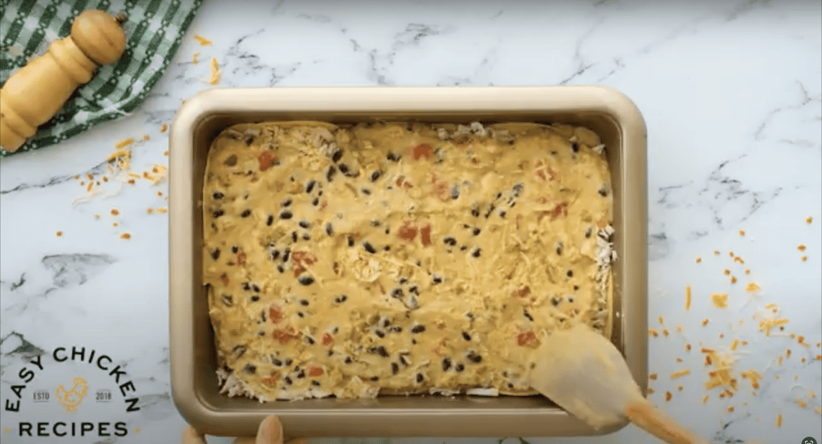 Using a rubber spatula to spread casserole mixture.