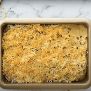 Unbaked casserole topped with shredded cheese.