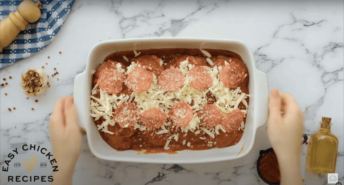 Pizza stuffed chicken breasts in a baking dish, topped with pepperonis and mozzarella.