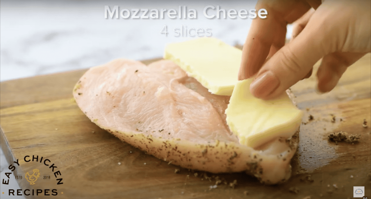 Placing pieces of mozzarella onto a butterflied chicken breast.