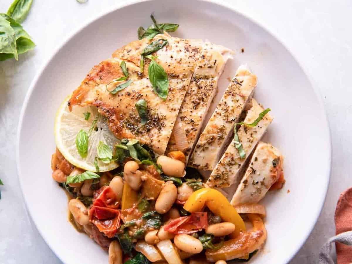 overhead view of sliced italian chicken breast on a white plate.