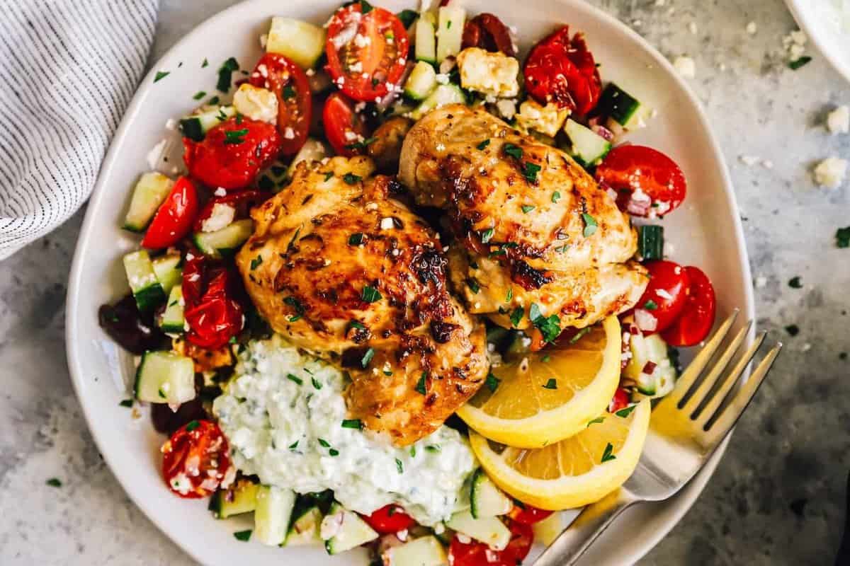 greek chicken thighs and greek salad on a plate