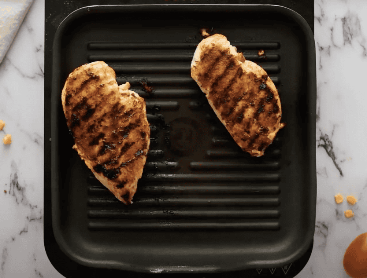 Two cooked chicken breasts on a grill pan.