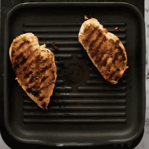 Two cooked chicken breasts on a grill pan.