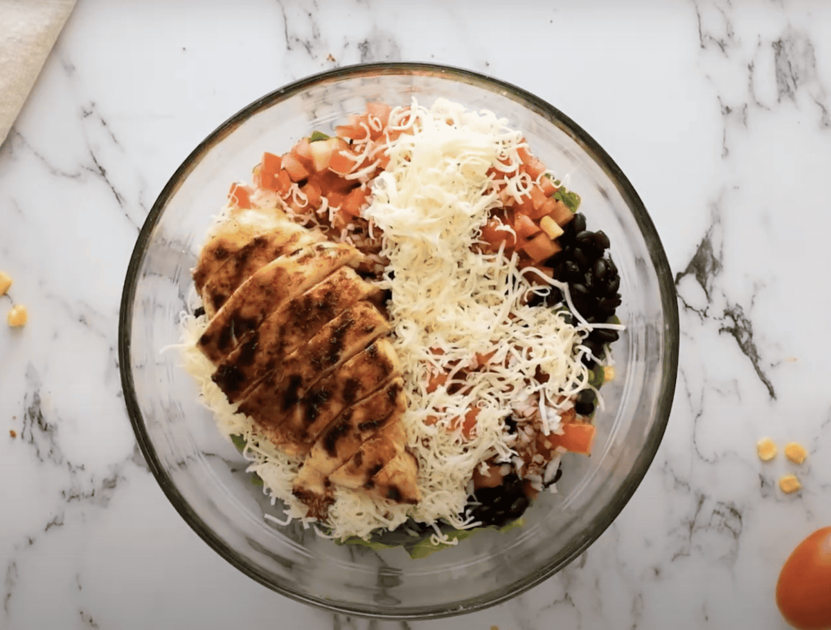 Salad topped with sliced BBQ chicken breast.