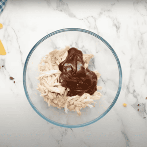 Rotisserie chicken and bbq sauce in a glass bowl.