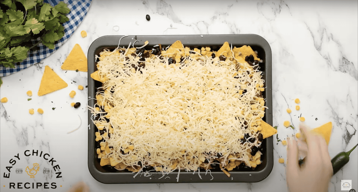 Baking tray filled with tortilla chips and shredded cheese.