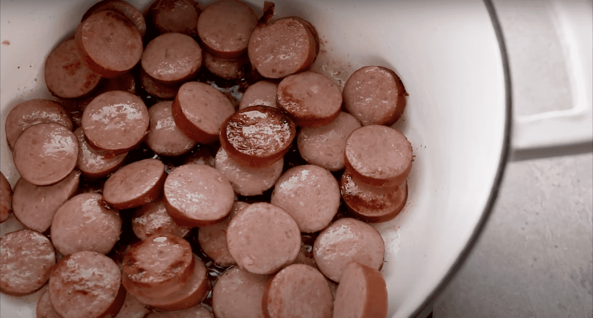 Sausage rounds cooking in a Dutch oven.