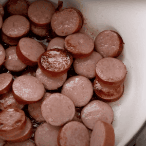 Sausage rounds cooking in a Dutch oven.