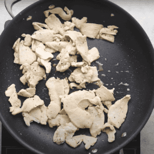 Slices of chicken cooking in a pan.