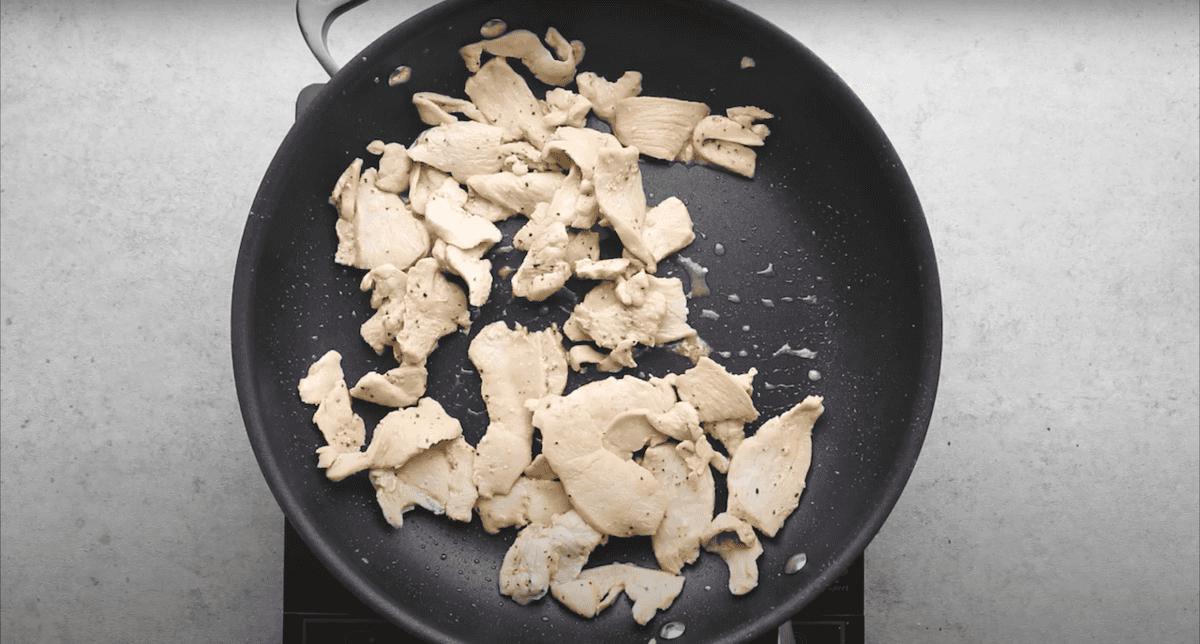 Slices of chicken cooking in a pan.